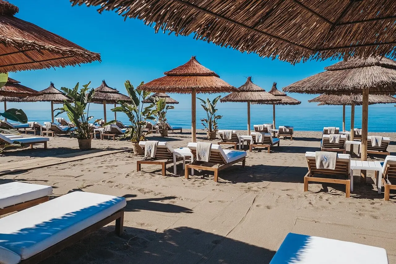 Strand van Estepona met luxe ligbedden en rieten parasols, op enkele minuten van Capri Estepona