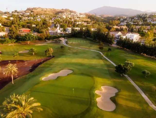 Groene fairways van een golfbaan in Estepona met uitzicht op de heuvels, direct naast Capri Estepona